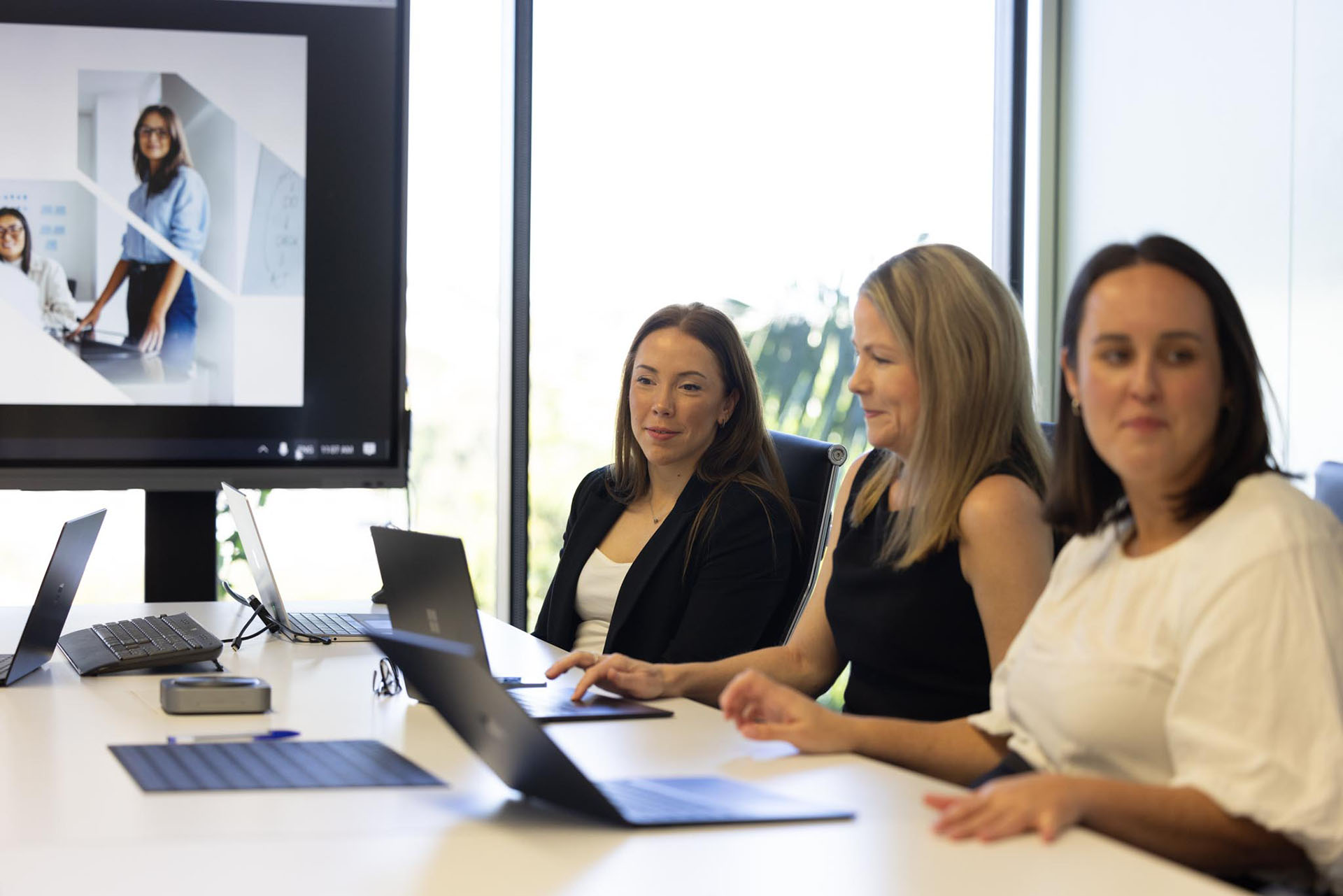 2 office ladies seated at a desk looking at a laptop