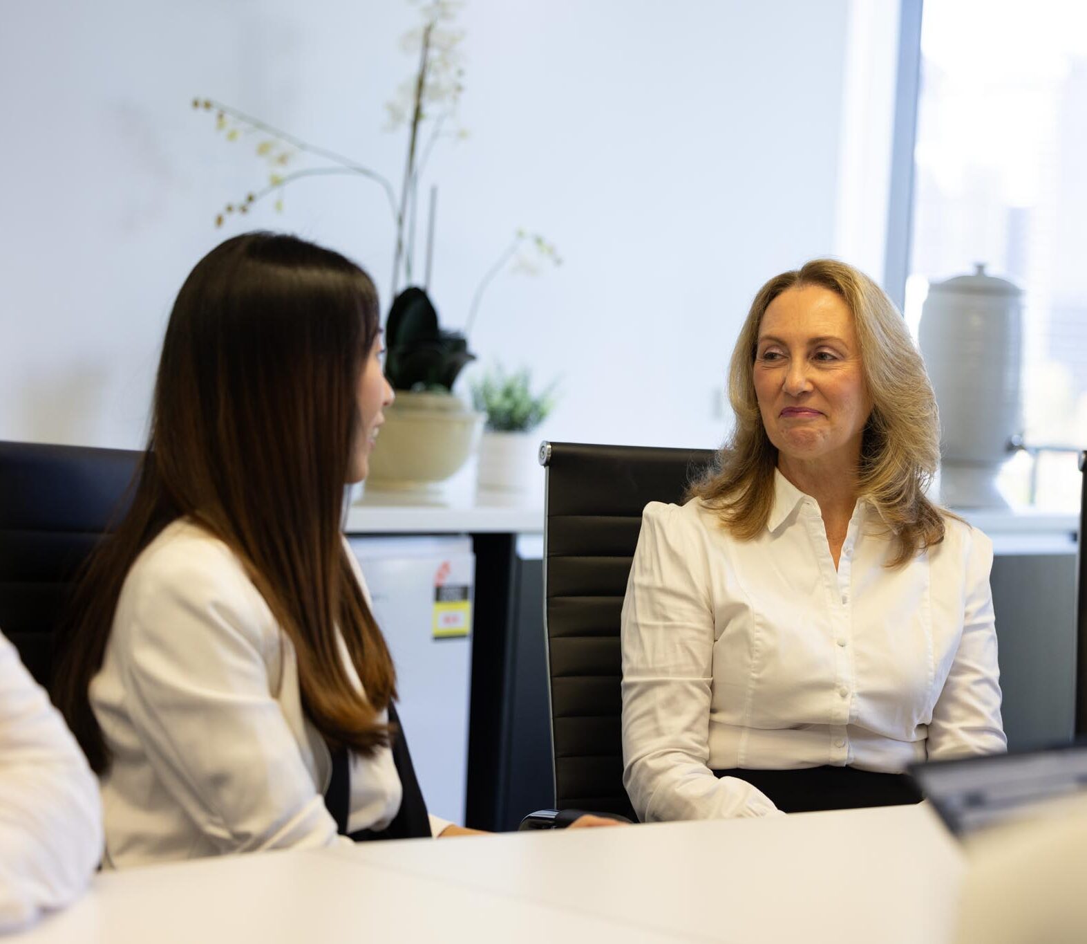 2 office ladies seated at a desk in discussion